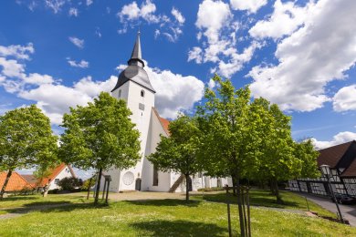 Gotische Stiftskirche Levern mit hohem Turm im Ortskern in grüner Landschaft 