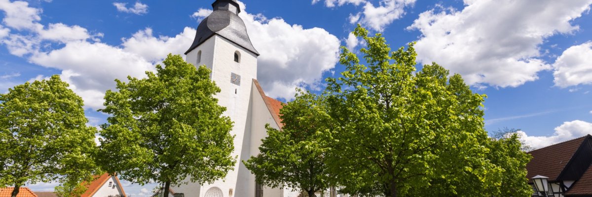 Gotische Stiftskirche Levern mit hohem Turm im Ortskern in grüner Landschaft 