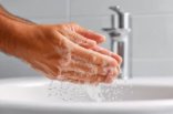 Hände die unter einem Wasserhahn gewachen werden.