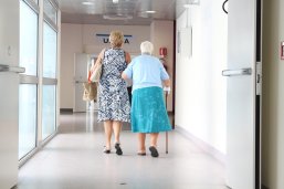 53_5_Einrichtungen Eine alte Dame wird von einer Pflegrin über einen Flur geführt