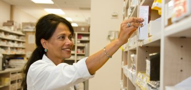 53_1_Apothekenwesen Eine Apothekerin nimmt Medikamente aus einem Regal.