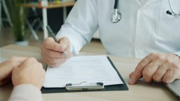Ein Arzt füllt ein Formular aus