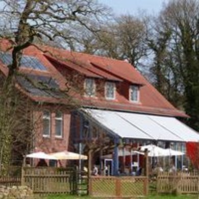 Café Gut Nordholz Ansicht auf das Gebäude des Cafés Gut Nordholz, rotes Backsteinhaus mit einem Außenbereich zum Sitzen, überdacht von einer Markise