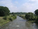 In der Mitte befindet sich ein Fluss, daneben viel Grün und ein Fuß- und Radweg 