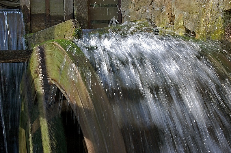 Wasserrad einer Wassermühle, welches aktiv ist und durch das Wasser läuft.