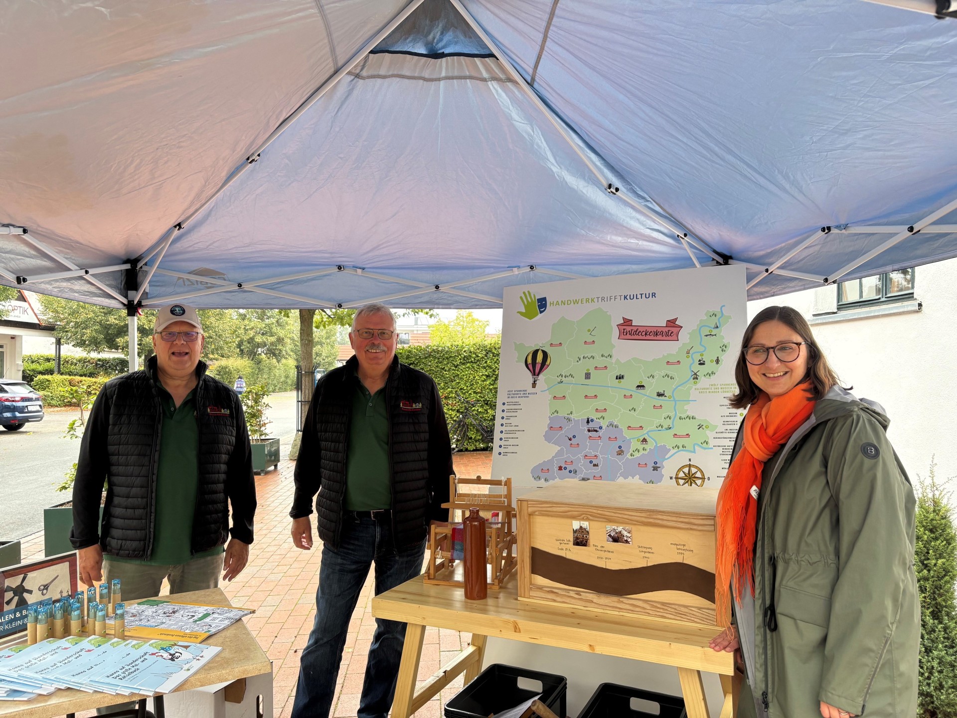 Bernd Beyer und Günter Ossenfort vom Museum „Alte Brennerei“ des Heimat- und Gartenbauvereins Hille e.V. freuen sich mit der Kulturkoordinatorin Daniela Daus (v.l.) über die Premiere der mobilen Ausstellung. Foto: Denise Vogelsang