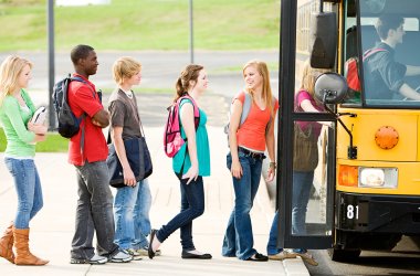 Eine Gruppe von Teenagern steht an einem Schulbus und steigt ein