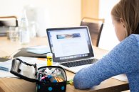 Mädchen sitzt am Notebook Schülerin sitzt am Notebook. Neben ihr liegt eine Federmappe, Bücher und Zettel.