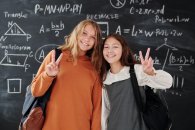 Mathe Zwei Mädchen vor einer Tafel mit mathematischen Formeln