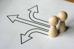 Menschen Weg Kreuzung Zwei Figuren vor denen drei Wegpfeile nach links, geradeaus und nach rechts verlaufen.